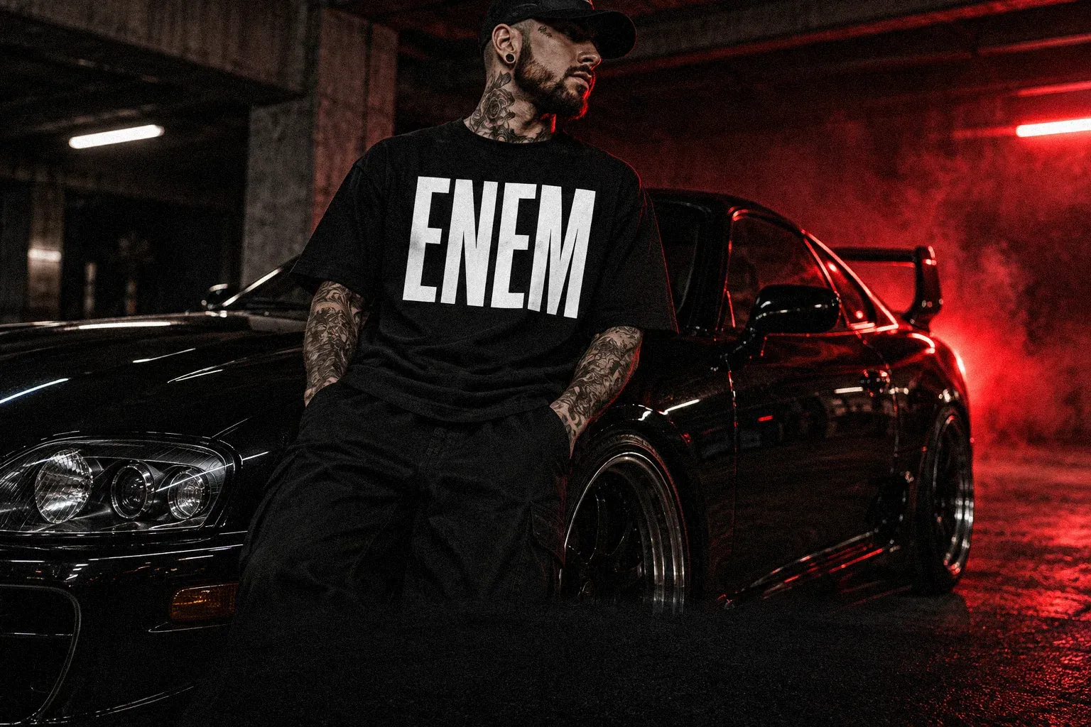 ENEM Car Culture: a man in an ENEM T-shirt beside a black sports car under red light