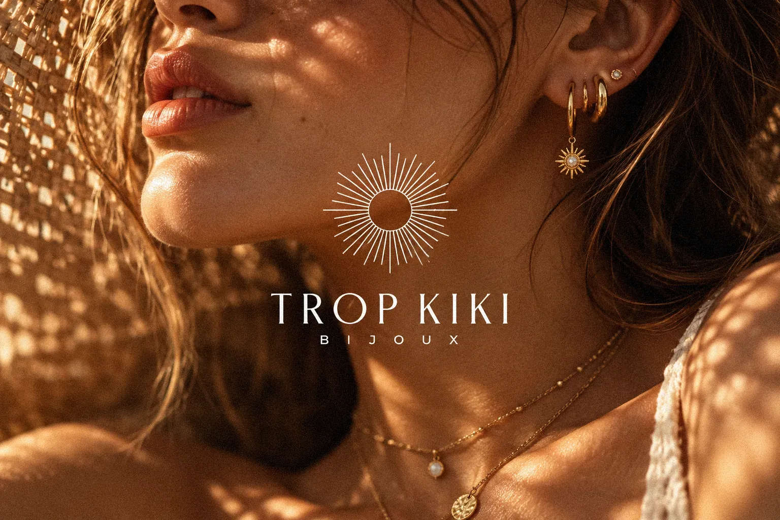 Trop Kiki: the sunburst Trop Kiki Bijoux mark over a woman wearing gold jewellery